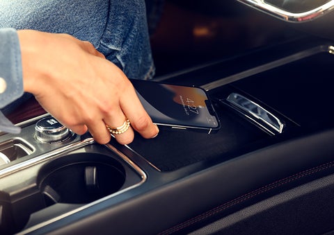 A smartphone is is being placed on the wireless charging pad in the front center console cubby. | Bluebonnet Motors Lincoln in New Braunfels TX