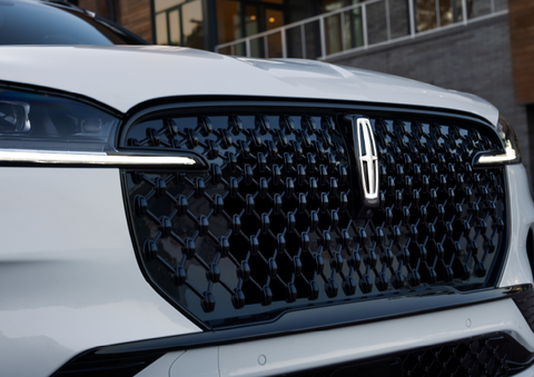 The black grille of a white 2025 Lincoln Aviator® SUV is shown with its fog lights on. | Bluebonnet Motors Lincoln in New Braunfels TX
