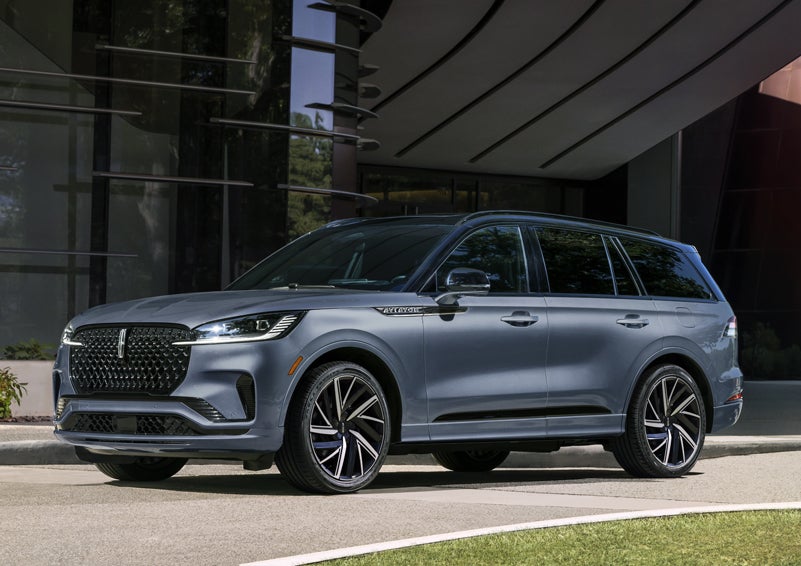A gray 2025 Lincoln Aviator® SUV is parked outside a modern building showcasing the driver’s side of the vehicle. | Bluebonnet Motors Lincoln in New Braunfels TX