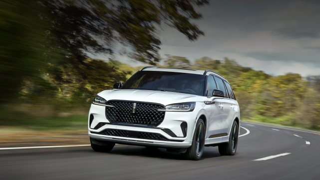 A white 2025 Lincoln Aviator® SUV is being driven down a road lined with trees. | Bluebonnet Motors Lincoln in New Braunfels TX