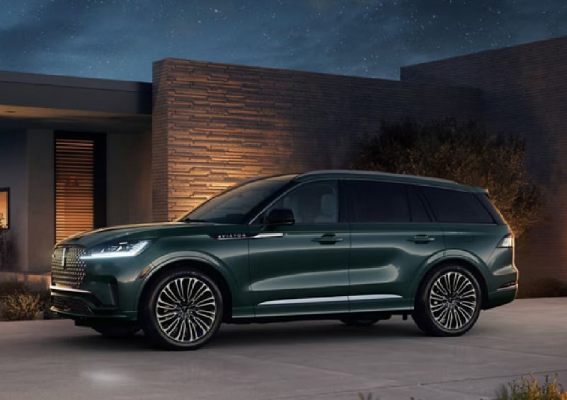A green 2027 Lincoln Aviator® SUV is parked outside a contemporary home. | Bluebonnet Motors Lincoln in New Braunfels TX