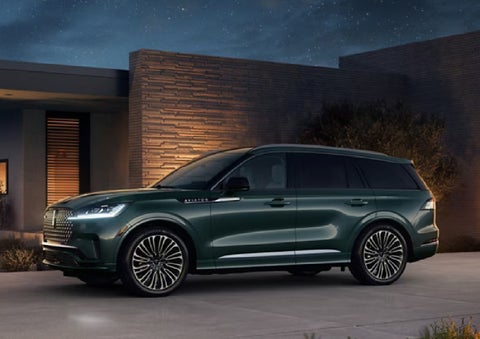 A green 2027 Lincoln Aviator® SUV is parked outside a contemporary home. | Bluebonnet Motors Lincoln in New Braunfels TX