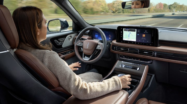 A 2027 Lincoln Aviator® SUV is being driven hands-free on a highway lined with trees. | Bluebonnet Motors Lincoln in New Braunfels TX