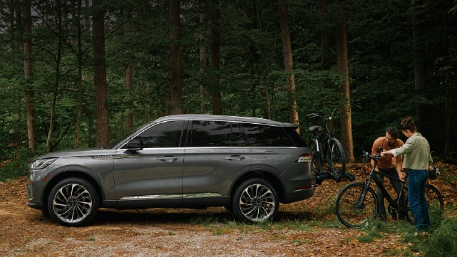 A father and son load e-bikes on a bike rack attached to a 2027 Lincoln Aviator® SUV. | Bluebonnet Motors Lincoln in New Braunfels TX