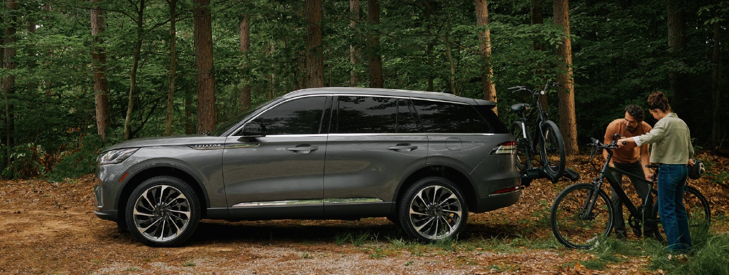 A father and son load e-bikes on a bike rack attached to a 2027 Lincoln Aviator® SUV. | Bluebonnet Motors Lincoln in New Braunfels TX